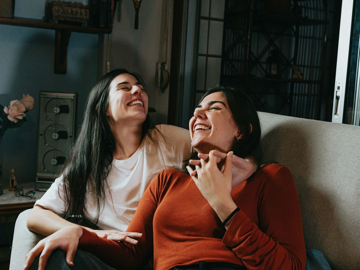 Two friends laughing together on a couch